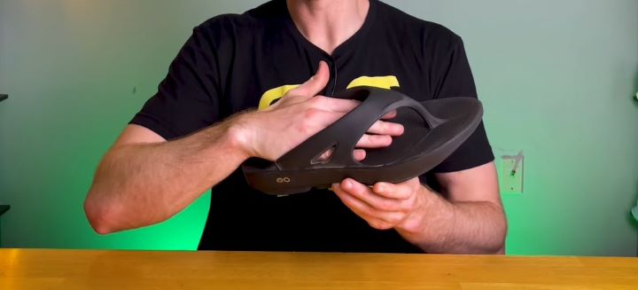 Touching the outer part of the flip flops to check its comfortability